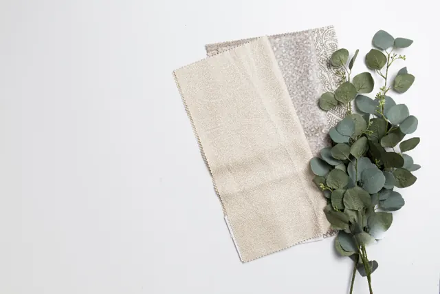 Fabric samples next to eucalyptus leaves on a white table